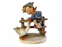 Front angle view of the Hummel Barnyard Hero #195 figurine showing the boy feeding a goose, mounted on an oval base.