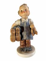 Front view of the Hummel figurine showing the child holding boots and a shoe, standing on a white base.