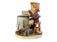 Side view showing boy seated at table with open book and dog at stool base