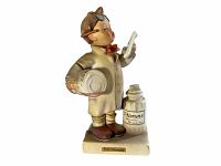 Front view of Hummel Little Pharmacist figurine showing figure holding pill bottle and reading paper with separate vitamins bottle on base.
