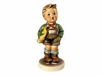 Front angled view of the Hummel Trumpet Boy figurine showing the figure holding a yellow trumpet, wearing a green jacket and brown shorts, standing on a round base.