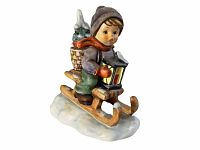 Front side view of child on sled holding lantern with basket of snow-covered trees behind, showing detail of face and clothing.