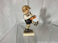 Side view of Little Drummer Hummel figurine showing the boy playing a drum, standing on a square base.