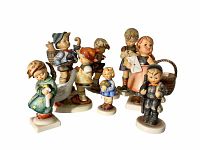 Front view of eight Hummel ceramic figurines showing varied poses and accessories, some with visible repairs or damage.