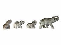 Side view of four porcelain elephant figurines arranged in size order from smallest to largest, showing poses and scale, white background