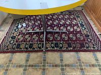 Full view of rectangular area rug with geometric floral pattern under a table on tile floor, showing rug and indirect view of pad underneath