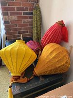 Group of five cloth lanterns in various colors and shapes on trunk