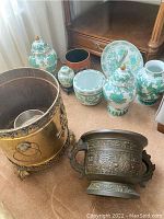 Overview of six porcelain pieces (jars, jardinière, plate) and three planters on carpet