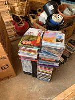 Stack of CDs in jewel cases on top and some media storage items and baskets in background