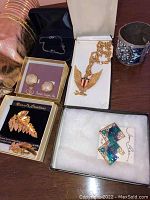 Photo showing gold-tone eagle pendant, gold leaf brooches, round rhinestone clip earrings, enamel blue-green earrings, and a silver-tone cuff bracelet