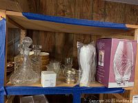 Shelf displaying the crystal decanter, candlesticks, ceramic bowls, glass bowls, Mikasa votive, creamer and sugar dishes, and boxed crystal vase