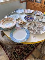 Photo of multiple decorative plates on a round table showing various designs and patterns