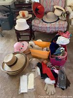 Overview of various women's hats, scarves, gloves, and hat boxes arranged on furniture and bins.