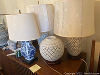 Three lamps and a vase displayed on wood surface