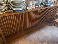Front view of wooden buffet with vertical slatted doors and lower shelf