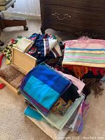 Overall pile of various pashminas and scarves on carpet showing colors and patterns