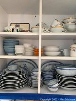 Photo showing various dinnerware including blue and white plates, cups, and bowls on shelves.