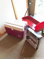 Photo of Radio Flyer wagon, Igloo Legend 58 cooler, and boxed charcoal grill positioned on a carpeted floor inside a shed.