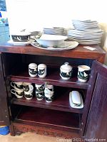 Full set of Sango Quadrille 5101 china pattern including plates, bowls, mugs, and accessories arranged in a wooden cabinet and surrounding area.