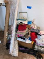 Overview of fabric remnants stacked against wall with large fabric rolls and boxed materials