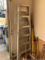 Full view of the six foot aluminum ladder leaning against wall.