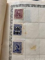 Three stamps from US and Uruguay mounted on album page with ornate borders, including one discontinued spot on page