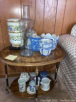 Wide shot showing all vases and pots arranged on a small round wooden table next to a sofa, capturing the variety and sizes of the items.