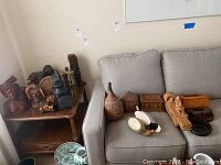 Overview photo showing multiple items on a table and sofa including carved busts, decoy ducks, wooden boxes, and lanterns.
