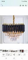 Assembled chandelier light fixture showing black vertical parts, gold accents, and hanging crystal drops.