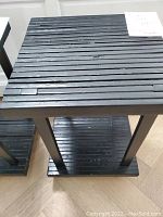 Close-up of the wooden slatted top surface painted black, showing minor scratches and paint chips.