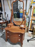 Full view of oak serpentine-front vanity dresser with attached oval mirror