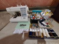 Overview photo displaying Kenmore 22 sewing machine with multiple sewing notions organized nearby in containers and trays.