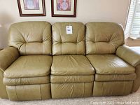 Front view of the olive green leather sofa, showing three seats with plush armrests and back cushions, all in very good condition.