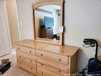 Front view of the 6 drawer dresser in light wood finish with small round knob handles and carved detail on drawers.