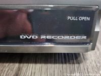 Close-up photo of the Sanyo DVD recorder front panel showing 'DVD Recorder' label with pull open slot.