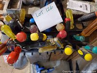 Top-down view of a rack holding multiple screwdrivers with colorful handles and a LOT 126 sign.