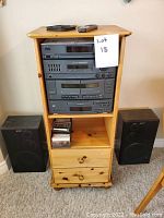 Full view of Sony stereo components installed in wooden cabinet with two drawers. Includes two matching black Sony speakers positioned on either side of cabinet. Drawer partially open showing CDs and cassette tapes inside.