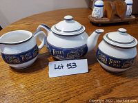 Photo showing the full Tetley Teas porcelain tea set of three: teapot, sugar bowl, and creamer arranged on a wooden table.