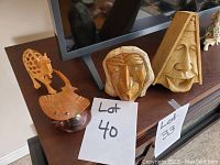 Photo of two wooden face carvings and wooden stingray on table below TV.