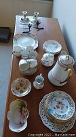 Full assortment of china including coffee pot, cups, saucers, plates, sugar bowl, cream pitcher, and candlesticks arranged on table.