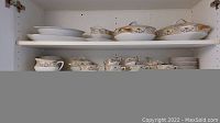 Shelf view of stacked dinner plates, side plates and lidded serving dishes