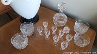 Full set with decanter, seven dessert dishes, eight aperitif glasses, and lidded salt dish on wooden table.
