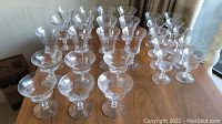 Photo showing the full assortment of 28 crystal dessert glasses in three sizes on a wooden surface.