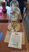 Full view of clock under glass dome with manual and winding key on table