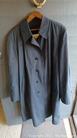 Front view of gray London Fog overcoat hanging on wooden hanger.