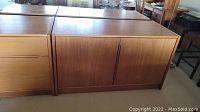 Full view of two-door teak wood Mid Century Modern cupboard with integrated handles and wood grain finish.