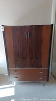 Front view of the wardrobe showing two wooden doors, lower drawers, and clear acrylic base legs.