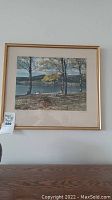 Full view of framed 'October in the Okanogan' art print showing lake, trees, and dog