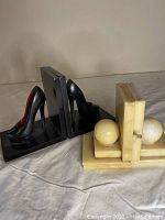 Side view of modern black high heel shoe bookends with a pair of vintage alabaster bookends showing spherical accents.