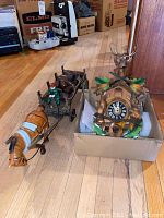Photo showing the cuckoo clock in its cardboard box next to the cast iron horse and cart figurine on a wood floor.